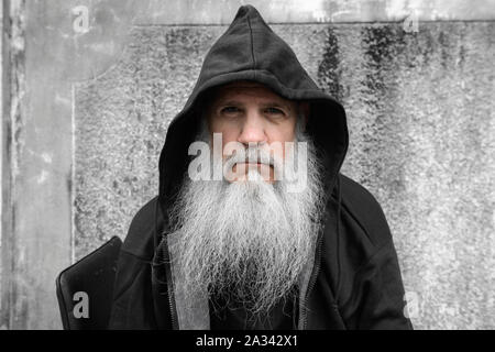 Reifen glatzköpfige Mann mit langen grauen Bart tragen Hoodie im Freien Stockfoto