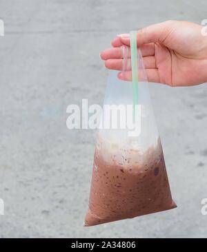 Trinken, Trinken, Hand Hodling thai Eiskaffee oder Eisschokolade im Beutel. Stockfoto