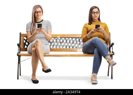 Zwei junge Frauen, die auf einer Bank sitzen und tippen auf Smartphones auf weißem Hintergrund Stockfoto