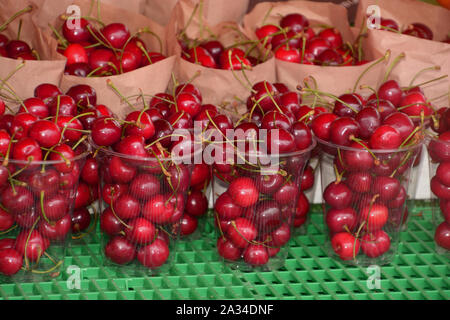 Low fat Kirschen in Plastikbecher und Säcke aus Papier, Ready-to-rote reife Kirschen in plastic container Street Market Essen Stockfoto