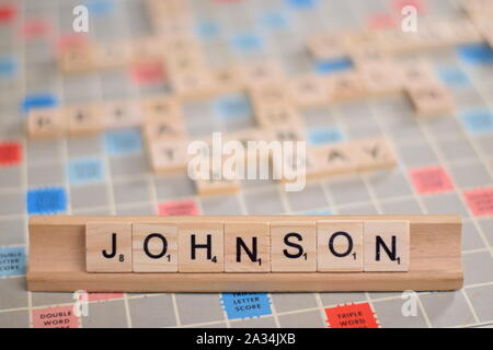 Der Name "Johnson" (Boris Johnson, Premierminister von Großbritannien, Brexit) in Holz- Scrabble Fliesen auf einem Baugruppenträger. Hintergrund ein Brett, unscharf, kopieren. Stockfoto