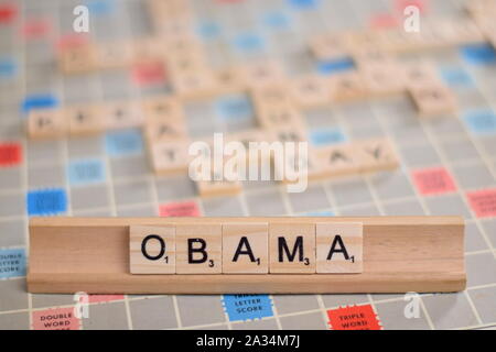 Der Name 'Obama' (Barack Obama, ehemaliger Präsident der USA) in Holz- Scrabble Fliesen auf einem Baugruppenträger. Hintergrund ein Vintage board, unscharf, kopieren. Stockfoto