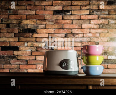 Bunte tiffin Träger und Toaster auf Holzschrank mit alten Mauer Hintergrund gegen warmes Licht Stockfoto