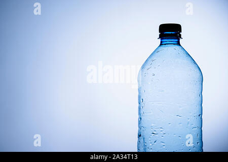 Klare Plastik Flasche Wasser oder Flüssigkeit mit Kondensation Tropfen auf der Oberfläche der Flasche über Blau mit Kopie Raum Stockfoto