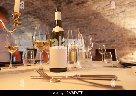 Restaurant Tabelle mit Vintage Tafelsilber, Flasche Weißwein mit leeren Etikett, Gläser, Besteck, Leuchter, Degustation im Weingut, ch Stockfoto