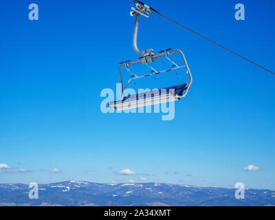 Leere Sessellift für Skifahrer und Snowboarder auf blauen Himmel Stockfoto