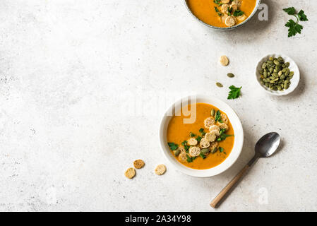 Kürbissuppe mit Croutons und Petersilie in Schalen auf weißem Hintergrund, Ansicht von oben, kopieren. Gesunde saisonale Ernährung Vegetarische Kost - hausgemachte Suppe. Stockfoto