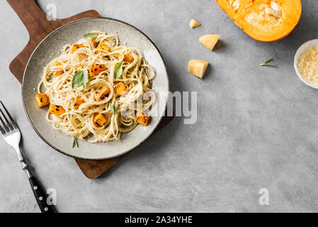 Kürbis Pasta auf konkreten Hintergrund, Ansicht von oben, kopieren. Saisonale vegetarische spaghetti Pasta mit gerösteten Kürbis, Sahne, geriebenen Parmesan und Salbei Stockfoto