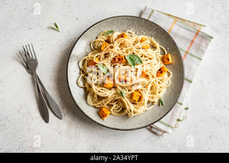 Kürbis Spaghetti auf weißem Hintergrund, Ansicht von oben, kopieren. Saisonale vegetarische spaghetti Pasta mit gerösteten Kürbis, Sahne, geriebenen Parmesan und Salbei Stockfoto