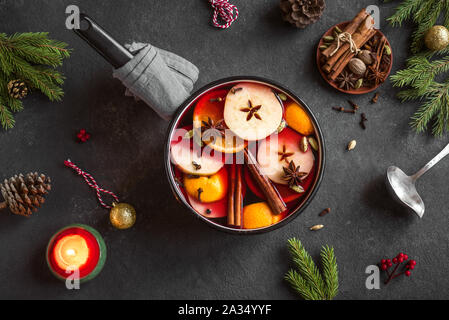 Glühwein für Weihnachten und Winter Urlaub. Heißer Glühwein trinken mit Früchte und Gewürze und Weihnachten Dekor auf schwarzem Hintergrund, Ansicht von oben. Stockfoto