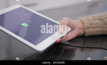 Frau, die PC-Tablet mit Symbol für schwache Batterien auf dem Bildschirm Stockfoto