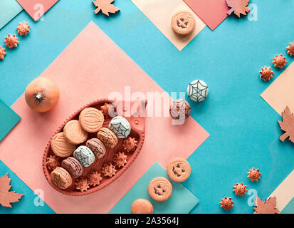 Halloween Hintergrund mit Kürbis Keksen, Makronen und Ahornblätter auf Split geometrische Papier Hintergrund in Pastellfarben Stockfoto