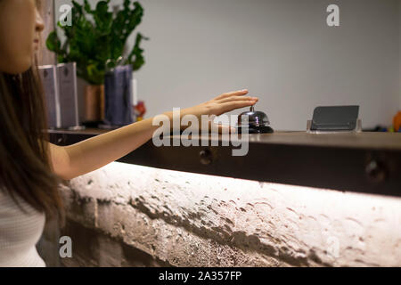 Close up Frauen rufen Sie das Hotel an der Rezeption auf dem Schreibtisch mit dem Finger drücken Sie eine Glocke in der Lobby Hotel. hotel Konzept. Stockfoto