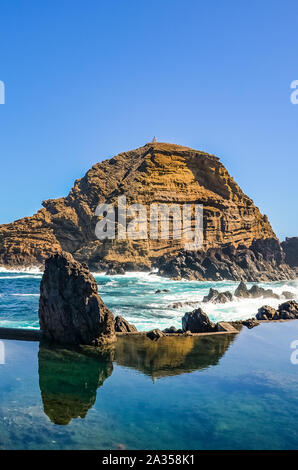 Wunderschöne natürliche Pools im Atlantischen Ozean, Porto Moniz, Madeira, Portugal. Aus Vulkangestein, in die das Meer natürlich fließt. Felsen im Hintergrund. Touristische Ort. Stockfoto