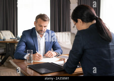 Ernsthafte Geschäftsmann und seine Kollegen arbeiten durch den Tisch im Restaurant Stockfoto