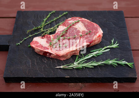 Raw Rib-eye-Steak auf dem Schwarzen Brett Stockfoto