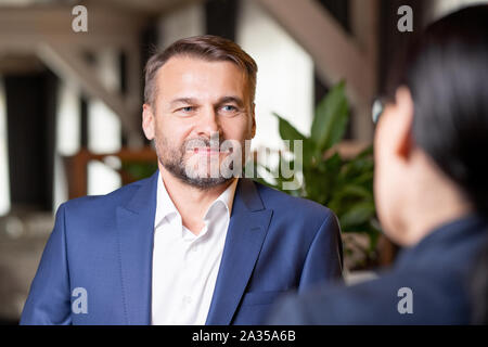 Happy bearded Geschäftsmann im eleganten Anzug Diskussion mit Kollegen Stockfoto