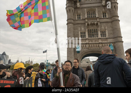 London, Großbritannien. Oktober 2019. Der chinesische Künstler Badiucao und Aktivisten aus Hongkong protestieren in der Nähe der Tower Bridge in London, Oktober 2019. Die Flagge der Lennon-Mauer wird im Rahmen der Demonstration deutlich sichtbar gezeigt. Die Teilnehmer tragen Masken und halten Plakate zur Unterstützung der Demokratie und der Menschenrechte in Hongkong. Penelope Barritt/Alamy Live News Stockfoto