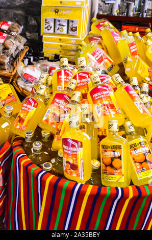 Porto da Cruz, Madeira, Portugal - Sep 24 2019: Korb mit kleinen Flaschen Poncha, traditionellen alkoholischen Getränken von Madeira. Typisch portugiesische alkoholische Getränk. Zuckerrohr Alkohol mit Fruchtsaft. Stockfoto