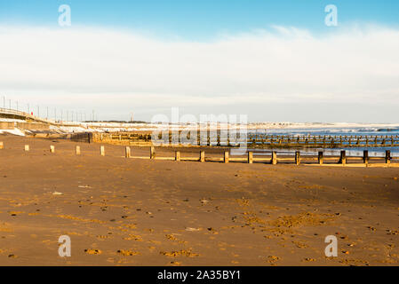 Braun sand Strand der Stadt mit Holz Wellenbrecher Beiträge in sonnigen Wintertag, Aberdeen, Schottland Stockfoto
