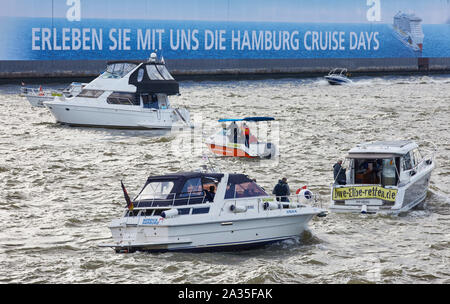 Hamburg, Deutschland. 05 Okt, 2019. Boote fahren in einer Protestaktion mit Banner mit der Aufschrift: 'Dove Elbe speichern" eine Parade vor den Landungsbrücken im Hamburger Hafen. Die Demonstranten befürchten, dass die Dove Elbe an der Tatenberg Verriegelung in Richtung der nördlichen Elbe öffnen könnte und damit eine Flutwelle Wasser werden mit Ebbe und Flut. Quelle: Georg Wendt/dpa/Alamy leben Nachrichten Stockfoto