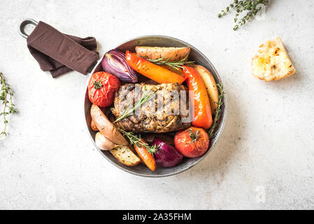 Gebratenes Fleisch und Gemüse auf weißem Hintergrund, Ansicht von oben, kopieren. Ofen gebackenes Schweinefleisch und Gemüse der Saison und Kräuter. Stockfoto