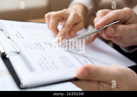 Ein Mensch der die Feder über das Papier beim Besprechen finanzielle Aufwendungen Stockfoto