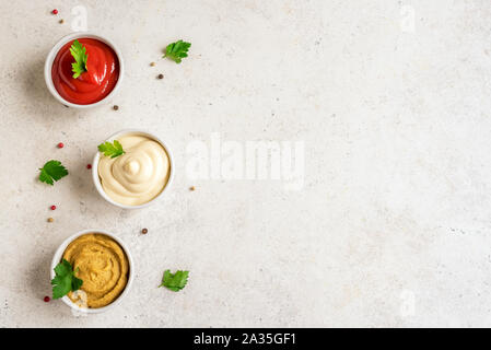 Drei klassische Saucen Ketchup, Mayonnaise und Senf auf weißem Hintergrund. Set der beliebten amerikanischen Saucen, Ansicht von oben, kopieren. Stockfoto