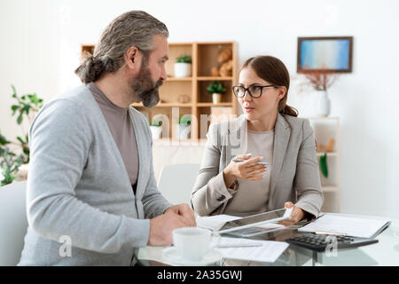 Junge real estate agent mit Touchpad Klienten hinsichtlich der Deal erklären Stockfoto