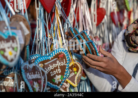 Hände von Frauen auf einem typischen Lebkuchenherzen auf dem Oktoberfest in München 2019 mit dem Wort Oktoberfest 2019. Stockfoto