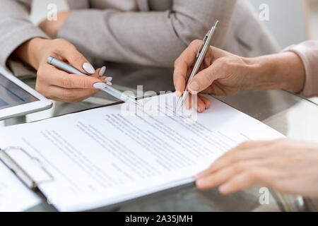 Menschliche Hände mit Stiften über finanzielle Dokument im Moment der Unterzeichnung Stockfoto