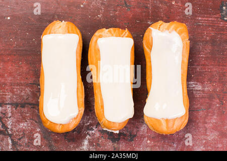 Drei eclair auf rotem Hintergrund. Traditionelle französische Dessert. Stockfoto