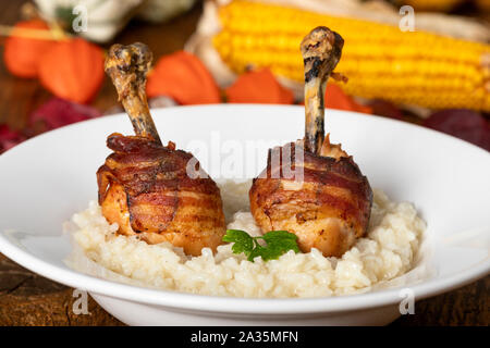 Hähnchenschenkel mit Speck auf Risotto Stockfoto