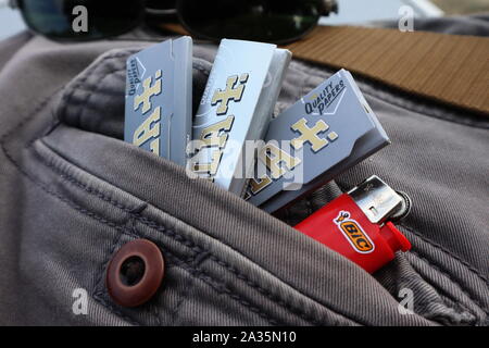 Pakete von Rizla zigarette Rolling Paper mit Bic mini in Tasche auf der Rückseite der grauen Jeans leichter Stockfoto