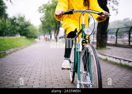 Fahrrad fahren im Regen. Nahaufnahme von Fahrrad Fahrer tragen gelbe Regenmantel Stockfoto