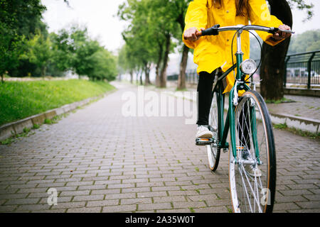 Fahrrad fahren im Regen. Nahaufnahme von Fahrrad Fahrer tragen gelbe Regenmantel Stockfoto