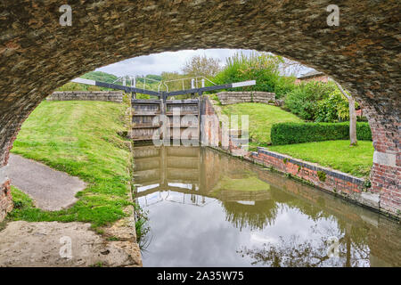 Schleusentore auf der Grantham Canal an Woolsthorpe von Belvoir durch den Bogen der Leinpfad Brücke gerahmt Stockfoto