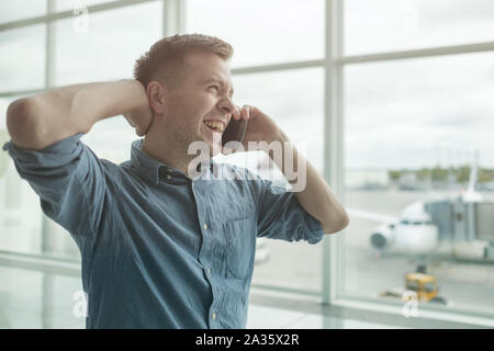 Jungen kaukasischen Mann Gespräch am Handy am Flughafen Stockfoto