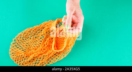 Null Abfall Konzept. Woman's Hand mesh Shopping Bag auf Grün. Flach banner Stockfoto