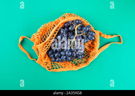 Null Abfall Konzept. Wiederverwendbare mesh Einkaufstasche mit frischen Weintrauben. Kunststoff Lifestyle. Herbst Obst Stockfoto