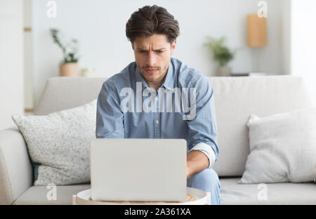 Mann bei der Arbeit am Laptop sitzen auf der Couch zu Hause Stockfoto