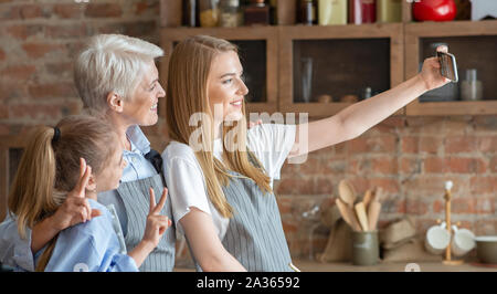 Seitenansicht von drei Frauen, die selfie in Küche Stockfoto