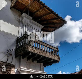 Cusco, Peru - 24.05.2019: Helle blaue Tür und Holz geschnitzten Balkonen im eleganten Zerfall in Cusco, Peru. Stockfoto