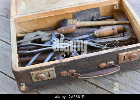 Einen Koffer mit alten Hand Tools auf einem Holz- Hintergrund. Fokus auf den Koffer. Stockfoto