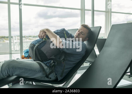 Reifer Mann im Flughafen schlafen im Terminal Stockfoto