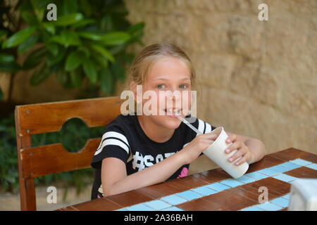 Kleines Mädchen trinkt Milch Cocktail in a Street Cafe. Sommerurlaub Stockfoto