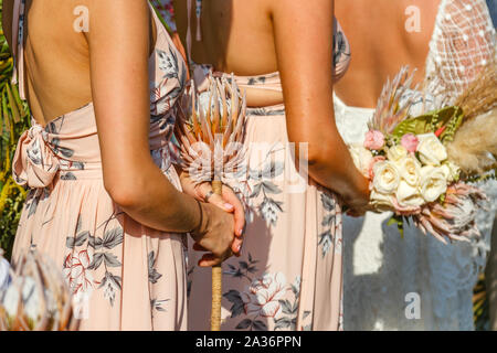 Brautjungfern und eine Braut mit Blumen und Blumensträuße, während einer Hochzeit stehen. Kein Gesicht. Stockfoto