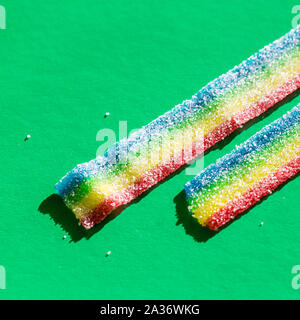 Lange regenbogenfarbenen Marmelade Süßigkeit. Versicolor Marmelade in der Zucker auf dem grünen Hintergrund. Platz kopieren, leere Vorlage für Text Stockfoto