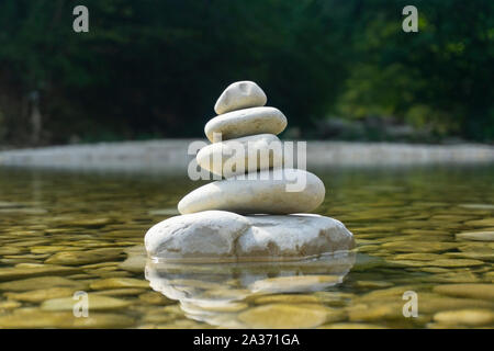 Harmonie, Ausgewogenheit und Einfachheit Konzept. Eine steinerne Pyramide auf dem Hintergrund von Flusswasser. Einfache poise Kiesel, Rock zen Skulptur, ein Turm von Rive Stockfoto