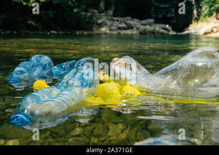 Kunststoff, die Verschmutzung des Flusses. Dirty Plastikflaschen und -tüten auf dem Müll. Die Verschmutzung der Flüsse, Kunststoff in Wasser. Umweltverschmutzung und Recyceln eco-Konzept. Stockfoto